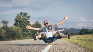 fun stock photo of a man and child sitting on a skateboard looking happy